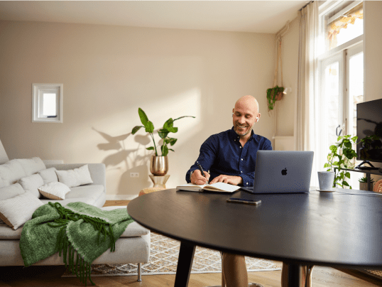 Man zit in woonkamer achter laptop